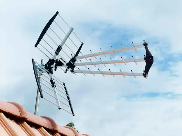 Technicien antenniste réglant une antenne TV